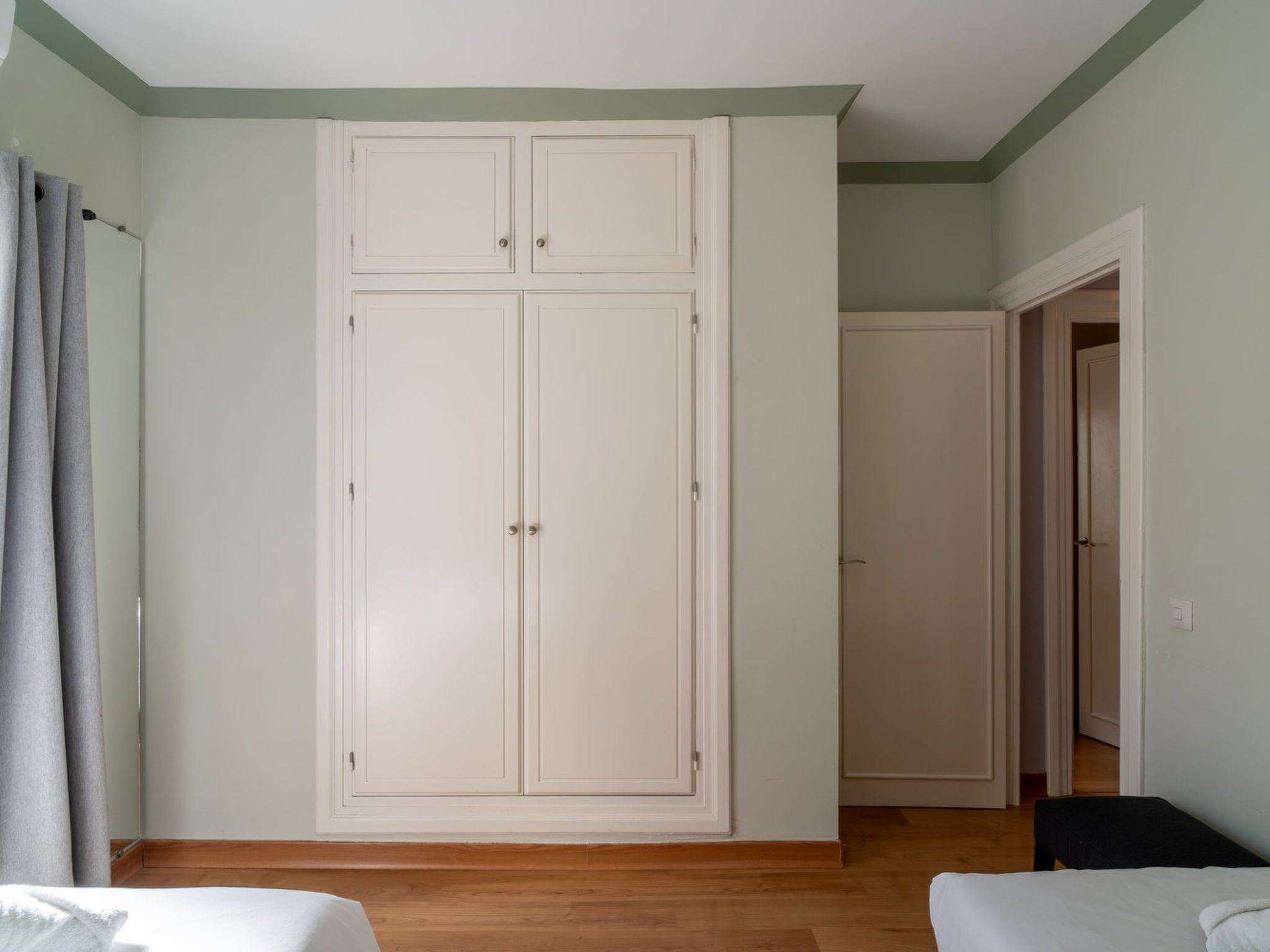 Ein Zimmer mit großem Kleiderschrank, Bett und Sitzbank.