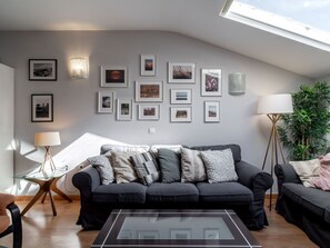 A modern living room with a black sofa, a glass coffee table, and a variety of framed pictures on the wall. - Bajamar Nerja II 7 by Casasol by Interhome (Nerja)