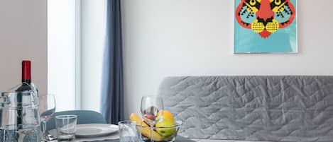 Comedor con una mesa dispuesta para dos personas, un cuenco de fruta y una botella de vino.