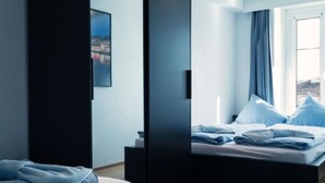 Ein modernes Hotelzimmer mit einem Bett, einem Nachttisch und einem fensterbepflanzten Fenster.