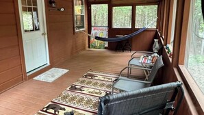 A wooden cabin with a porch, a hammock, and a table with chairs. -  1-bedroom off grid cabin in serene Woodville perfect for relaxing getaway (Woodville)
