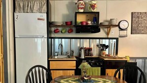 A compact kitchen with a refrigerator, a microwave, a sink, and a dining table with chairs. -  1-bedroom off grid cabin in serene Woodville perfect for relaxing getaway (Woodville)