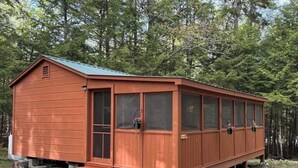A wooden cabin with a porch, windows, and a door. -  1-bedroom off grid cabin in serene Woodville perfect for relaxing getaway (Woodville)