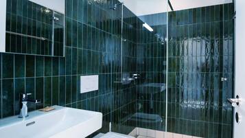 Ein modernes Badezimmer mit Duschkabine aus Glas, einem weißen Waschbecken und einer Toilette.
