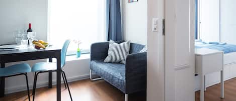 Una habitación moderna con zona de comedor, sofá y cama.
