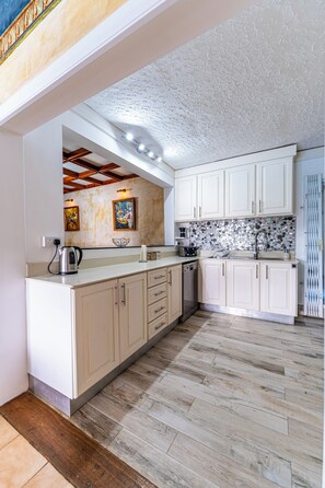 A kitchen with white cabinets, a tiled backsplash, and a wooden floor. - Wake up to the sound of waves. Enjoy your 13 m private pool. Watch the sunsets. (Flic en flac)