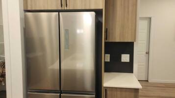 A kitchen with a stainless steel refrigerator, wooden cabinets, and a countertop.