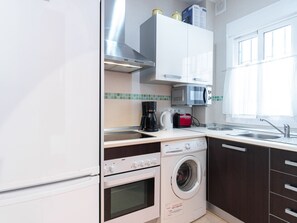 Cozinha compacta com forno embutido, micro-ondas e máquina de lavar.