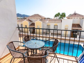 Ein Balkon mit Pool, Korbmöbeln und Blick auf benachbarte Gebäude.