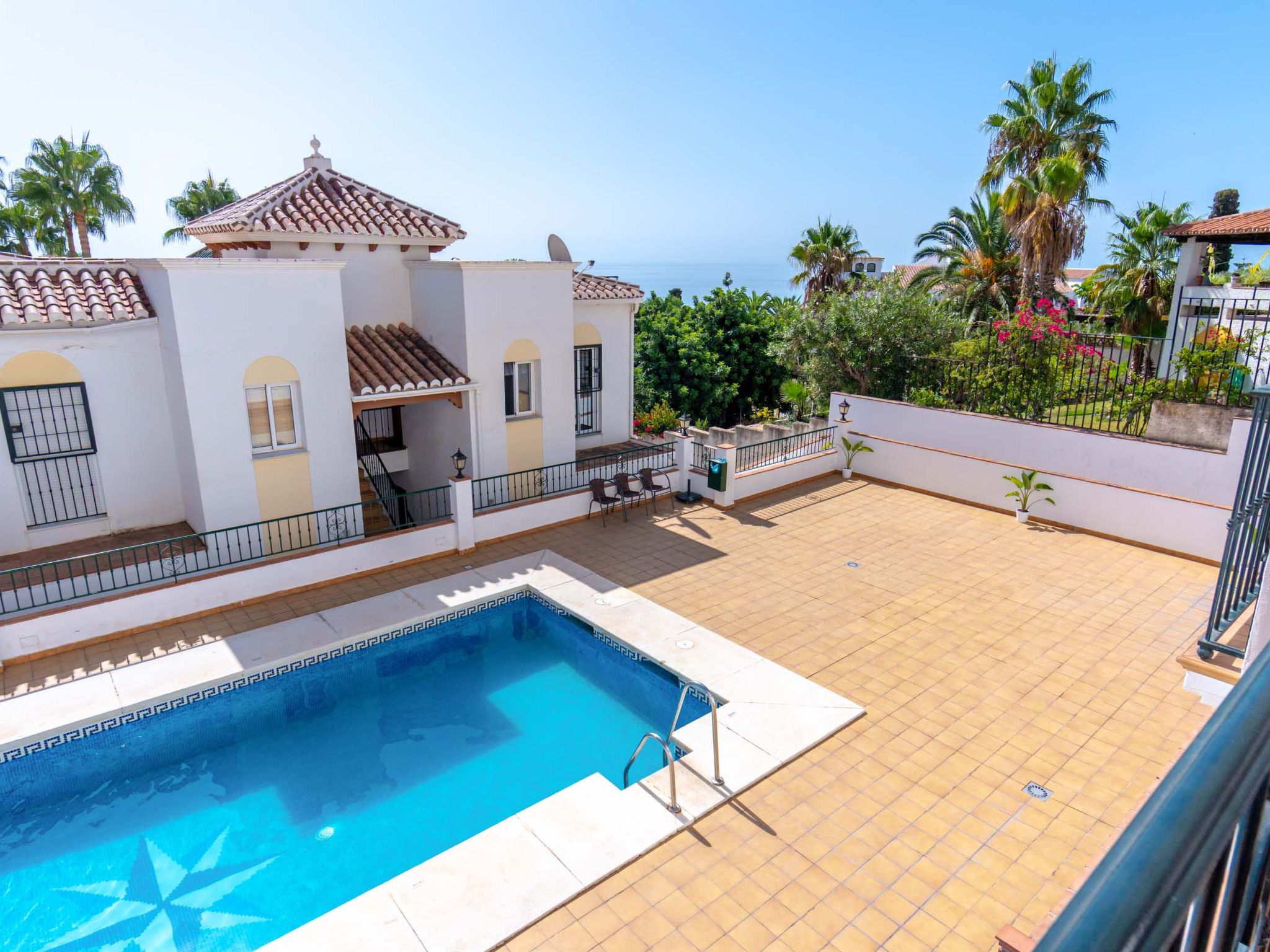 A residential property with a swimming pool, a covered patio, and a view of the sea.