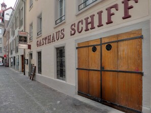 Un edificio con un letrero que dice 'GASTHAUS SCHIFF' y una puerta de madera con contraventana cerrada.