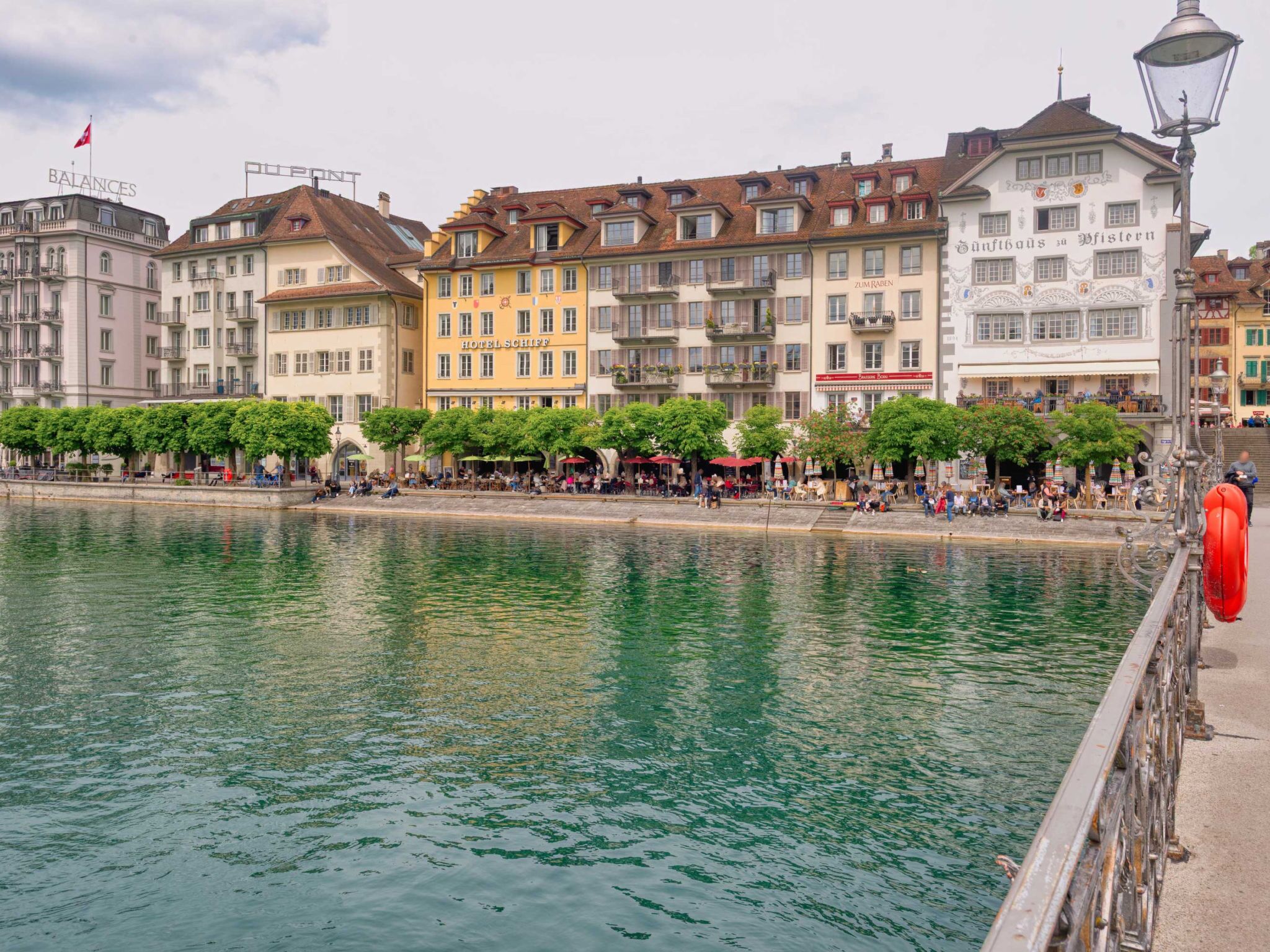 Eine Uferpromenade mit Gebäuden, darunter ein Hotel und ein Restaurant.