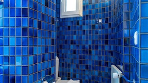 Ein Badezimmer mit blauen Fliesenwänden und einer weißen Toilette.