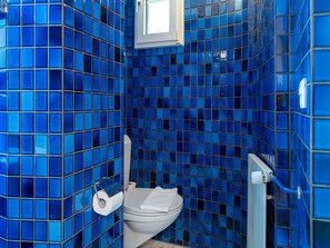Un baño con paredes de azulejos azules y un inodoro blanco.