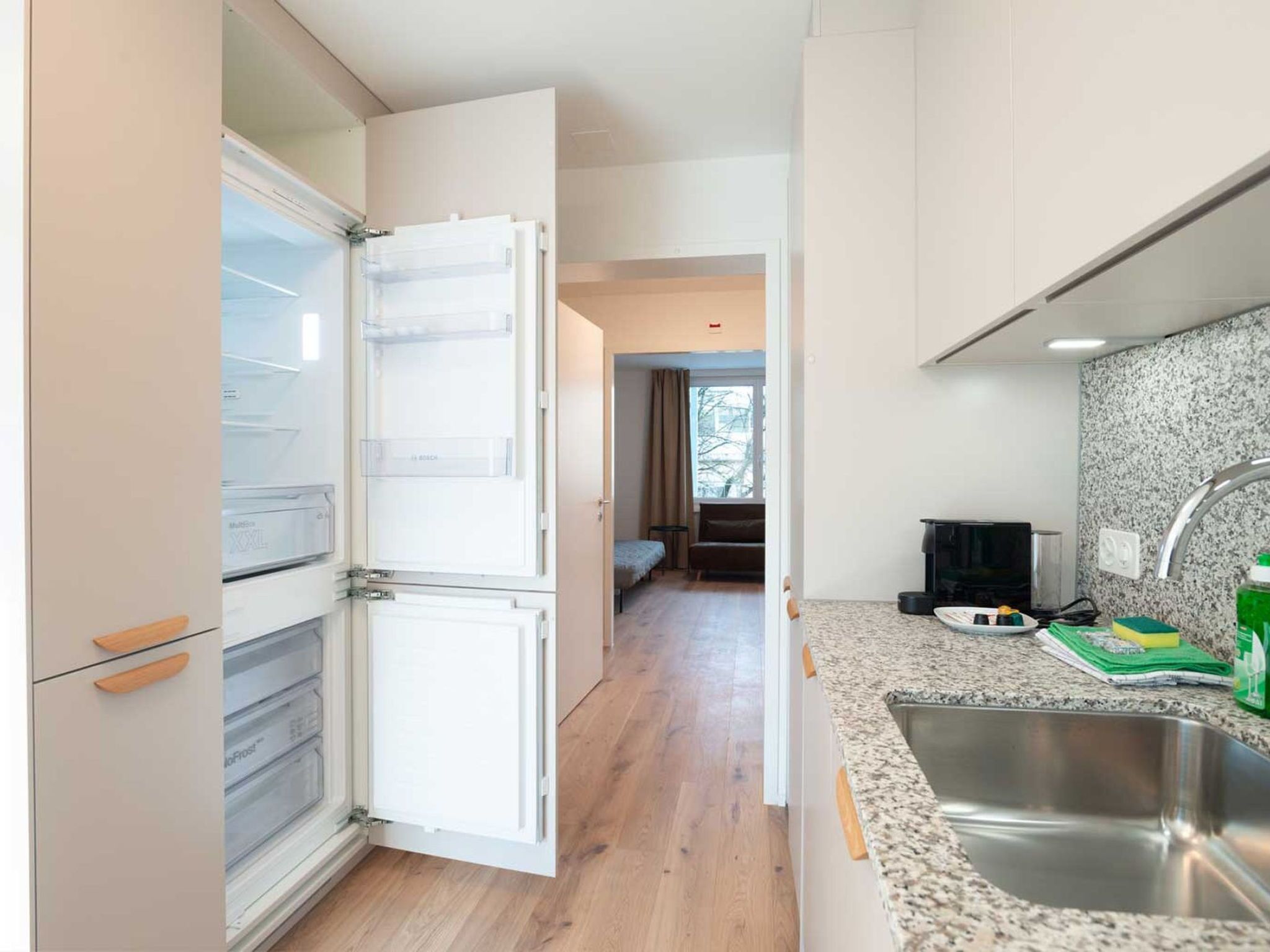 A modern kitchen with a stainless steel sink, a countertop with a dish soap bottle, and a microwave.