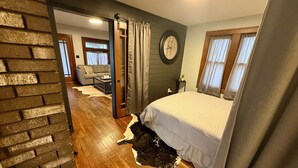 A bedroom with a bed, a clock, a sliding door, a sofa, and a coffee table. - 1-4 Guests, 1 Bath Farm Stay at a Pygmy Goat Farm in Byron Center, Michigan (Byron Center)