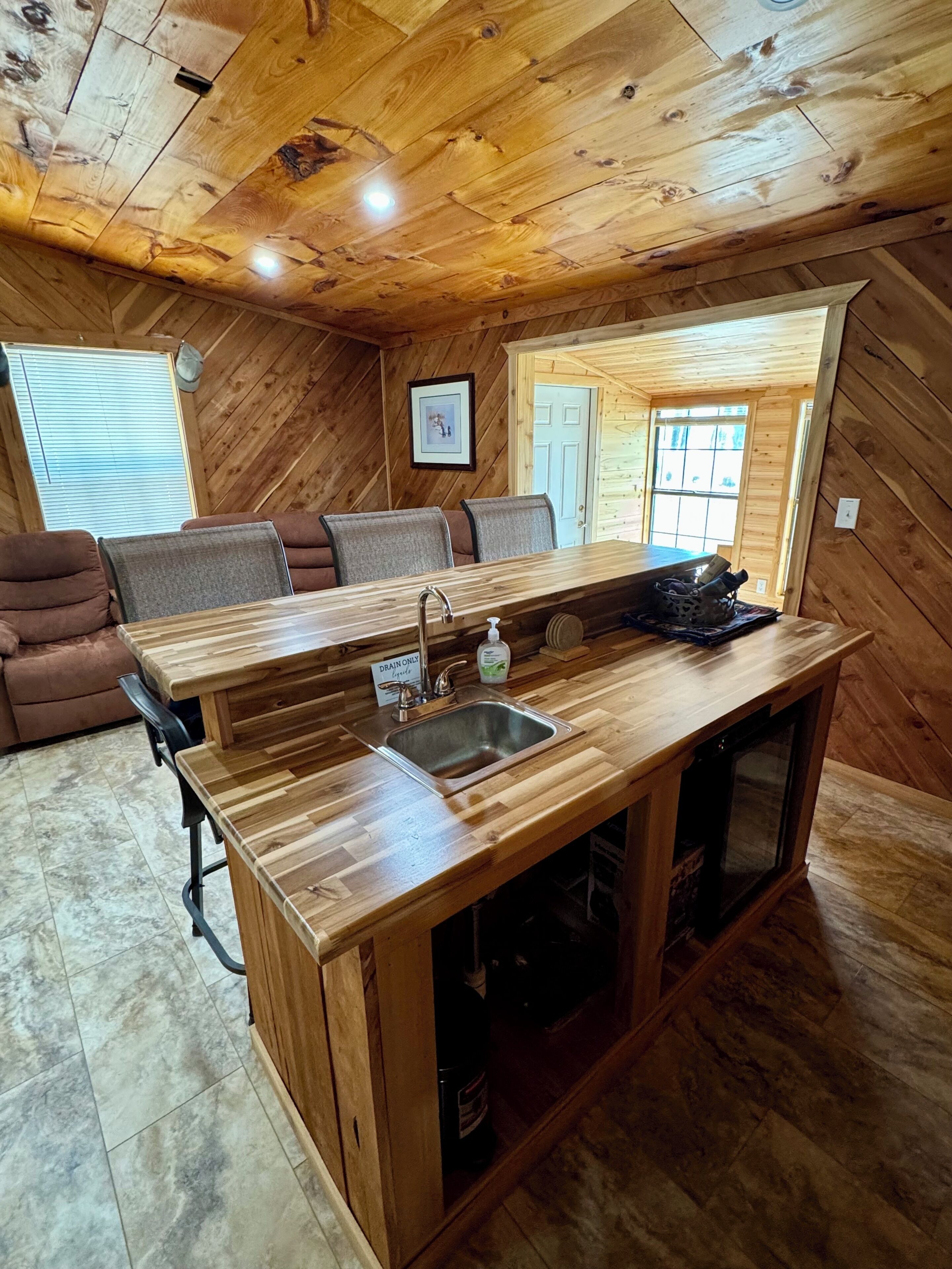 Un interno in legno con isola della cucina, angolo salotto e una finestra.