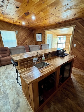 A wooden interior with a kitchen island, seating area, and a window.