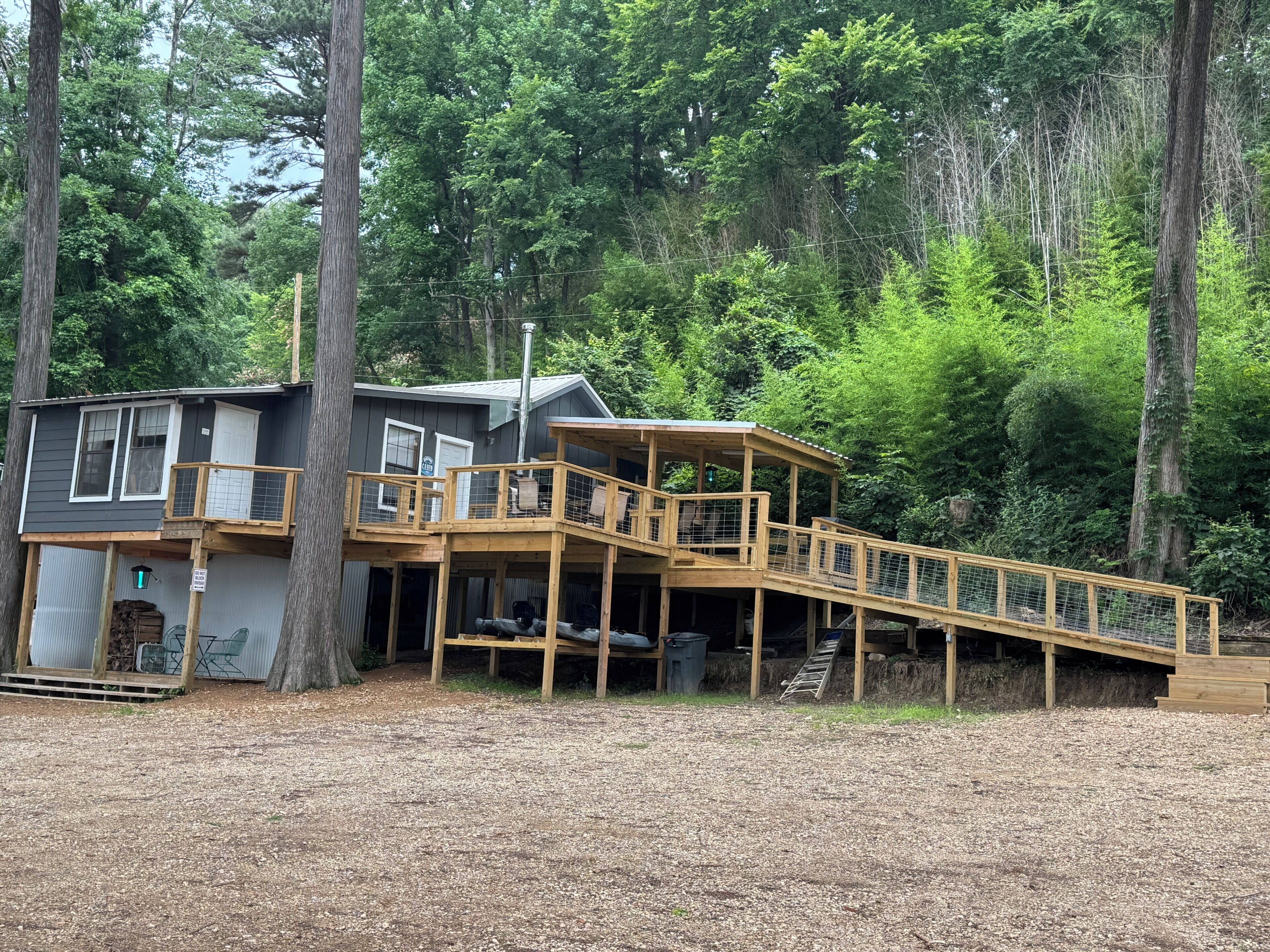 Eine zweistöckige Holzhütte mit einer Holzterrasse und einer Treppe zu einer überdachten Veranda.