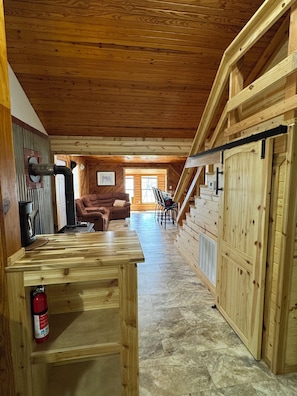 A wooden interior with a fireplace, a sofa, a dining table, and a staircase.