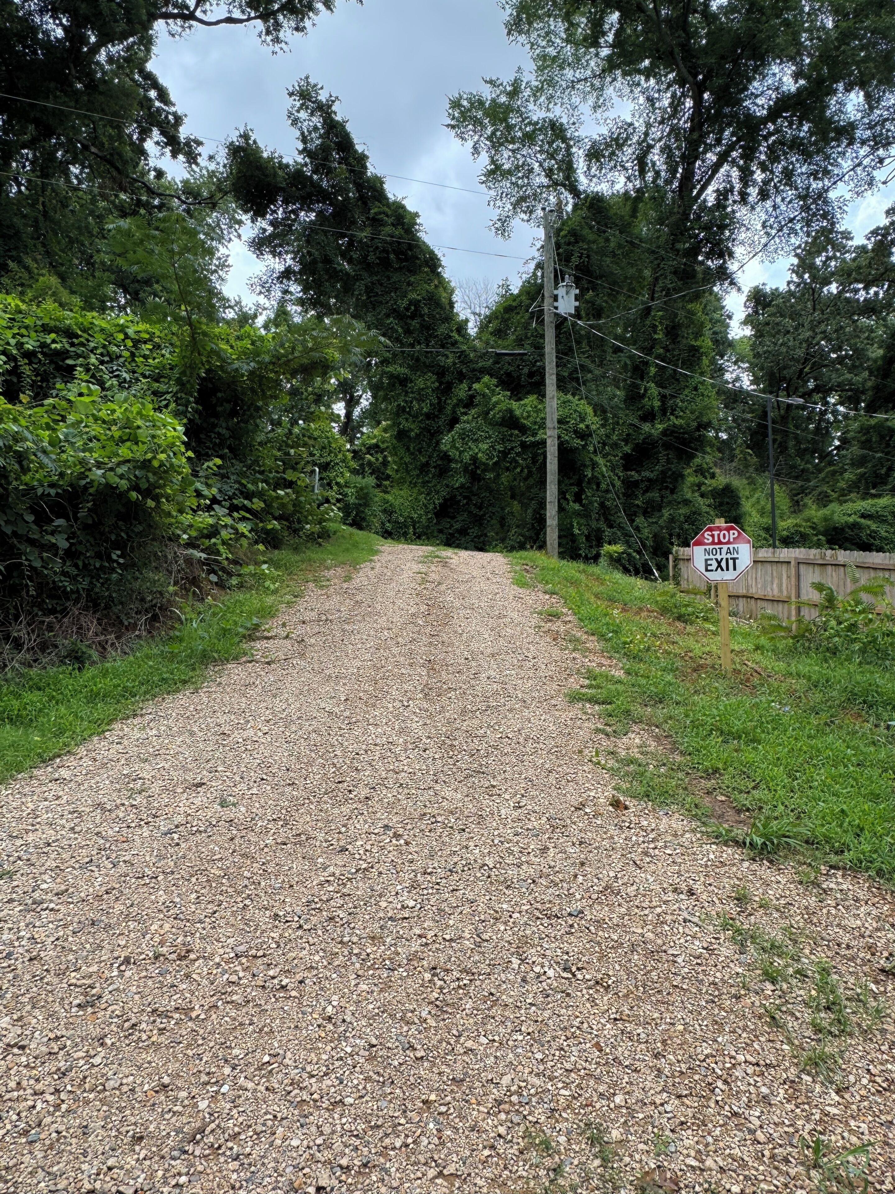 A gravel path leading through a wooded area with a stop sign indicating it's not an exit.