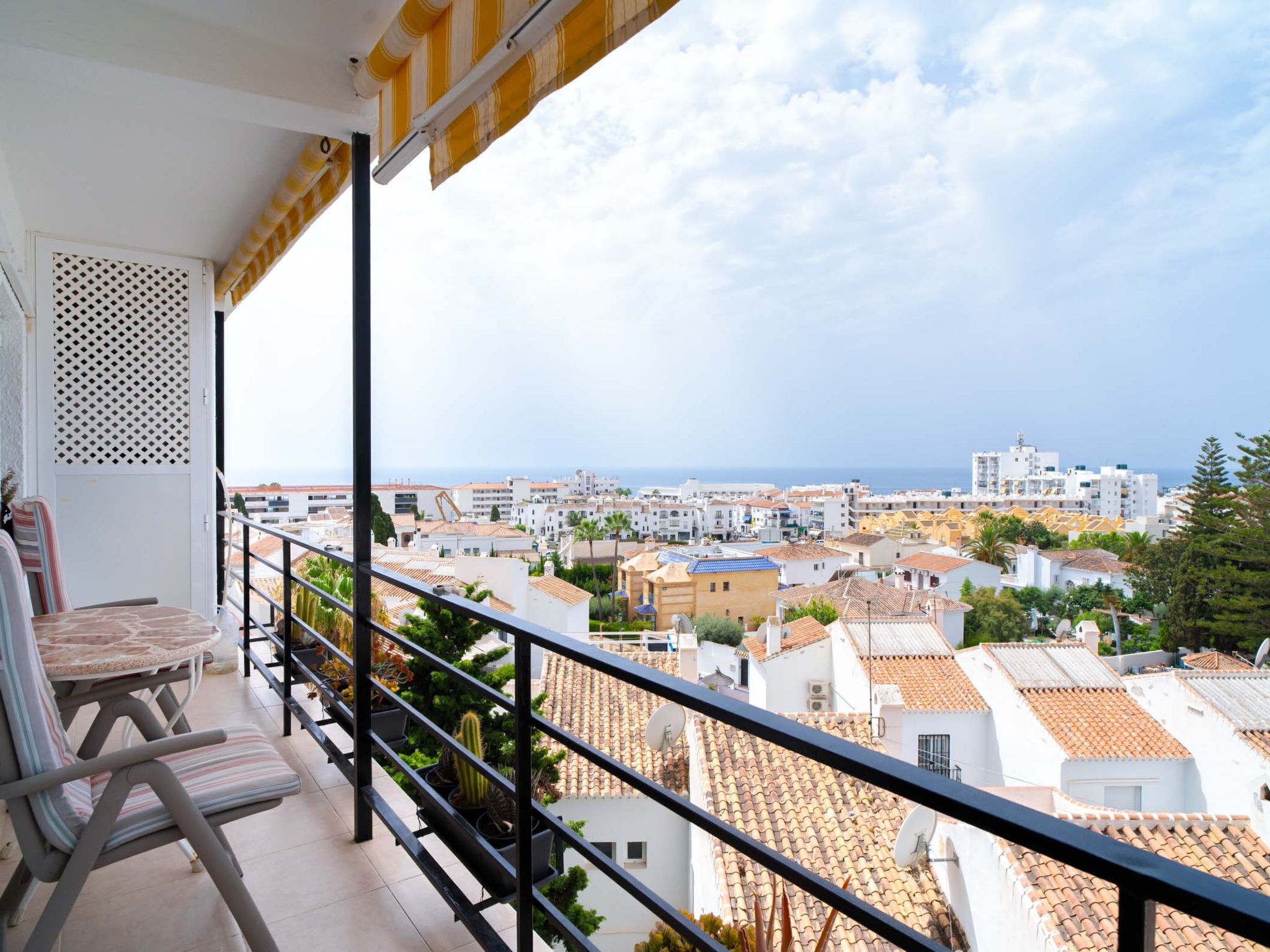 A balcony with a view of a coastal cityscape, including buildings and the sea.