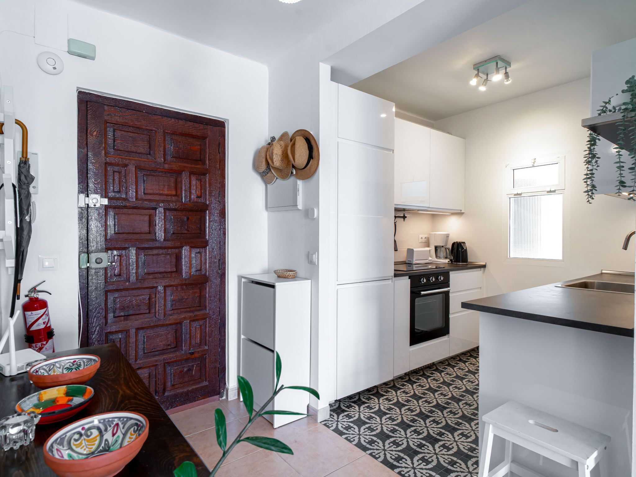 Una cocina compacta con armarios blancos, un horno negro y una pequeña encimera.
