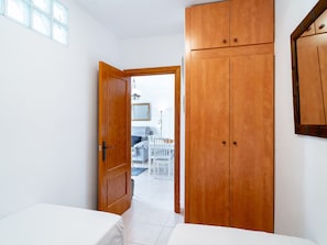 A room with a wooden wardrobe, a bed, and a dining area visible through an open door. - Capri Sunset by Casasol by Interhome (Nerja)