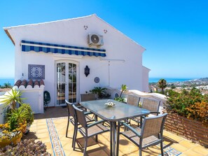 A white building with a blue awning, a glass door, and a table with chairs. - Apartment  by Interhome (Nerja)