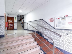 Eine Treppe mit gemusterten Fliesen und Metallgeländern, die zu einer Tür mit einem Schild führt.