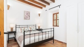 A bedroom with a bed, bedside tables, a nightstand, a wall-mounted lamp, a framed picture, a window, and a wardrobe. - Finca Can Nin by Interhome (Santanyí)