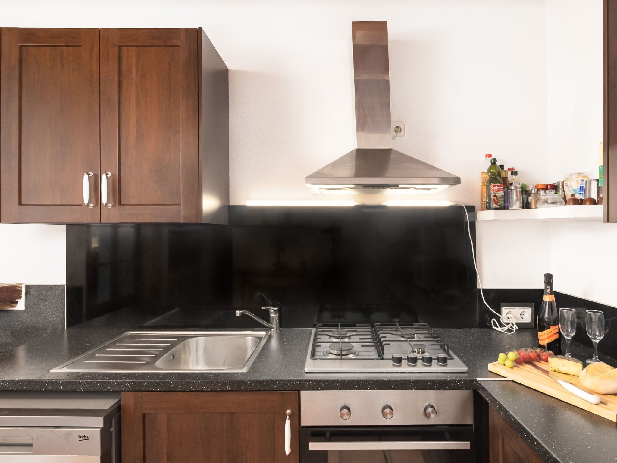 A modern kitchen with dark wood cabinets, stainless steel appliances, and a black countertop.