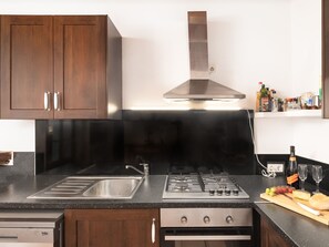 Una cocina moderna con gabinetes de madera oscura, electrodomésticos de acero inoxidable y encimera negra.