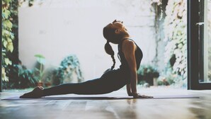 A person performing a yoga pose on a mat in a room with a large window and plants. - Finca Can Nin by Interhome (Santanyí)