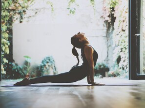 A person performing a yoga pose on a mat in a room with a large window and plants. - Finca Can Nin by Interhome (Santanyí)