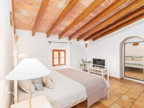 Un dormitorio con cama, televisor, ventana y vistas al exterior.