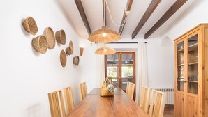 A dining room with a wooden table, chairs, a hanging light fixture, and a wooden cabinet. - Finca Can Nin by Interhome (Santanyí)