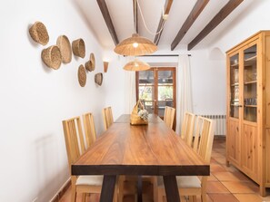 A dining room with a wooden table, chairs, a hanging light fixture, and a wooden cabinet. - Finca Can Nin by Interhome (Santanyí)