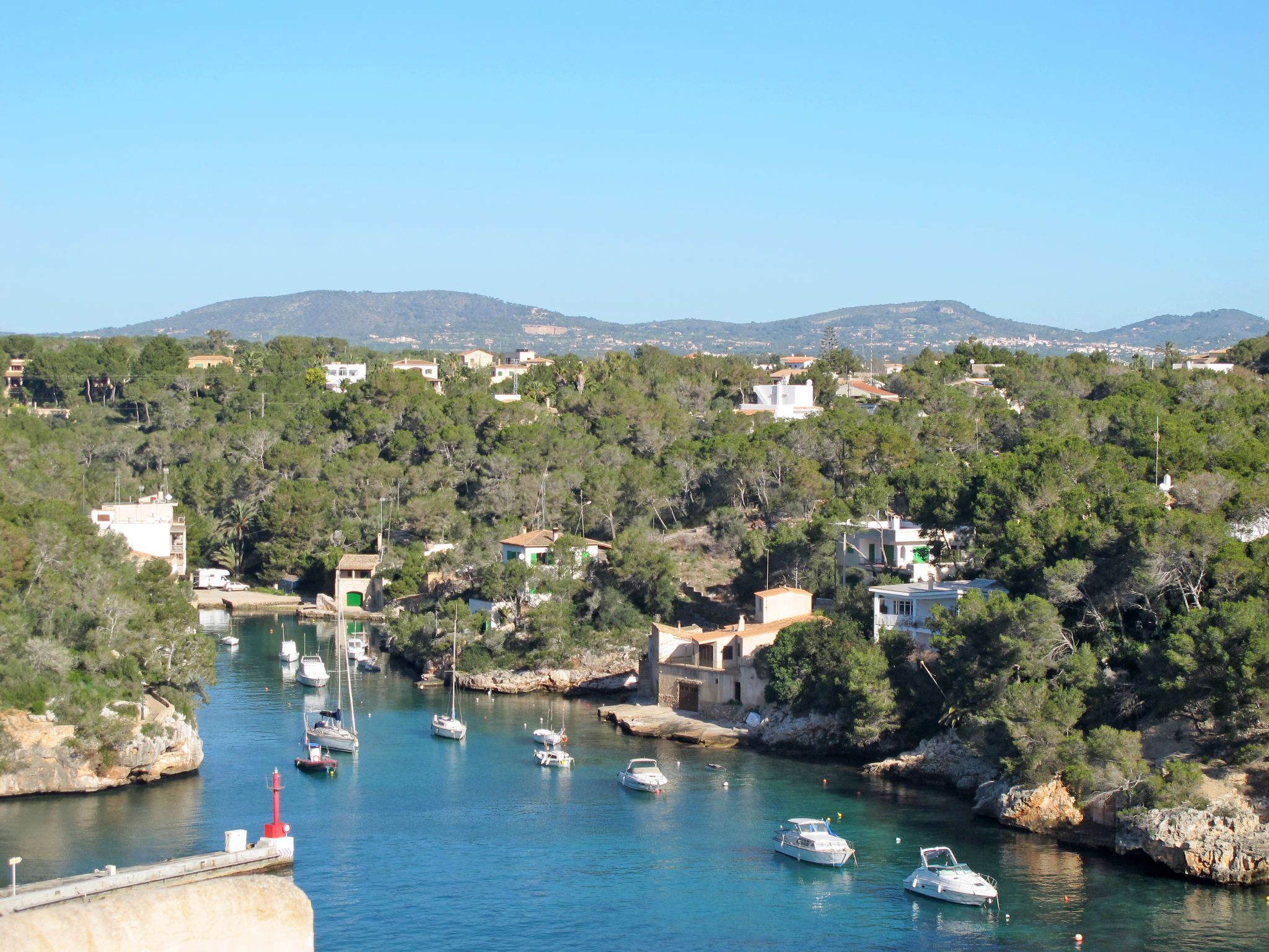 Un pueblo costero con barcos amarrados a lo largo del agua, rodeado de vegetación y edificios.