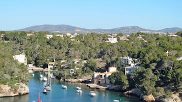 Un pueblo costero con barcos amarrados a lo largo del agua, rodeado de vegetación y edificios.