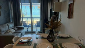 A dining area with a table set for four, a sofa, and a view of the outdoors. - Clócio 201 - Beachfront apartment on Cabo Branco beach (João Pessoa)