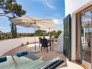 A rooftop terrace with a dining table, chairs, and a large umbrella. - Villa Redonda by Interhome (Santanyí)