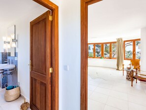 A room with a wooden door, a bathroom with a sink, and a view of an outdoor area with a table and chairs. - Villa Redonda by Interhome (Santanyí)