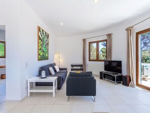 A modern living room with a sofa, a coffee table, a TV, and artwork on the wall. - Villa Redonda by Interhome (Santanyí)