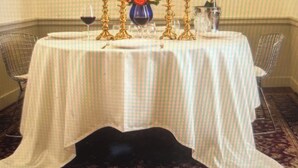 A table with a checkered tablecloth, candles, a vase with flowers, and a bottle of champagne. - Royal Place des Vosges, 2nd floor, 4 guest, Old World Charm (Paris)