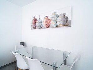 Een moderne eetruimte met een glazen tafel en witte stoelen.