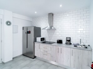 A modern kitchen with a stainless steel refrigerator, a microwave, a toaster, a coffee maker, and a sink. - Apartment  by Interhome (Nerja)