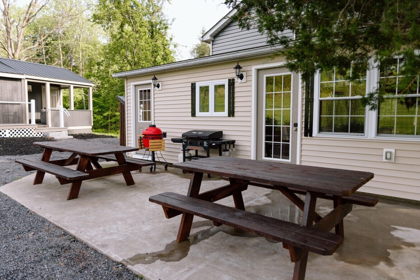 A house with a covered porch, a barbecue grill, and picnic tables.