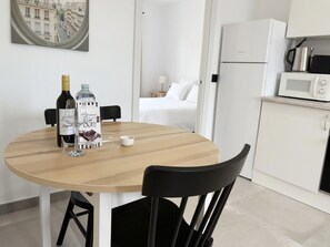Una cocina moderna con una mesa redonda de madera, un refrigerador blanco y un microondas.