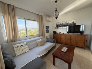Ein Wohnzimmer mit einer Couch, einem Couchtisch, einem Fernseher und einem Schrank.